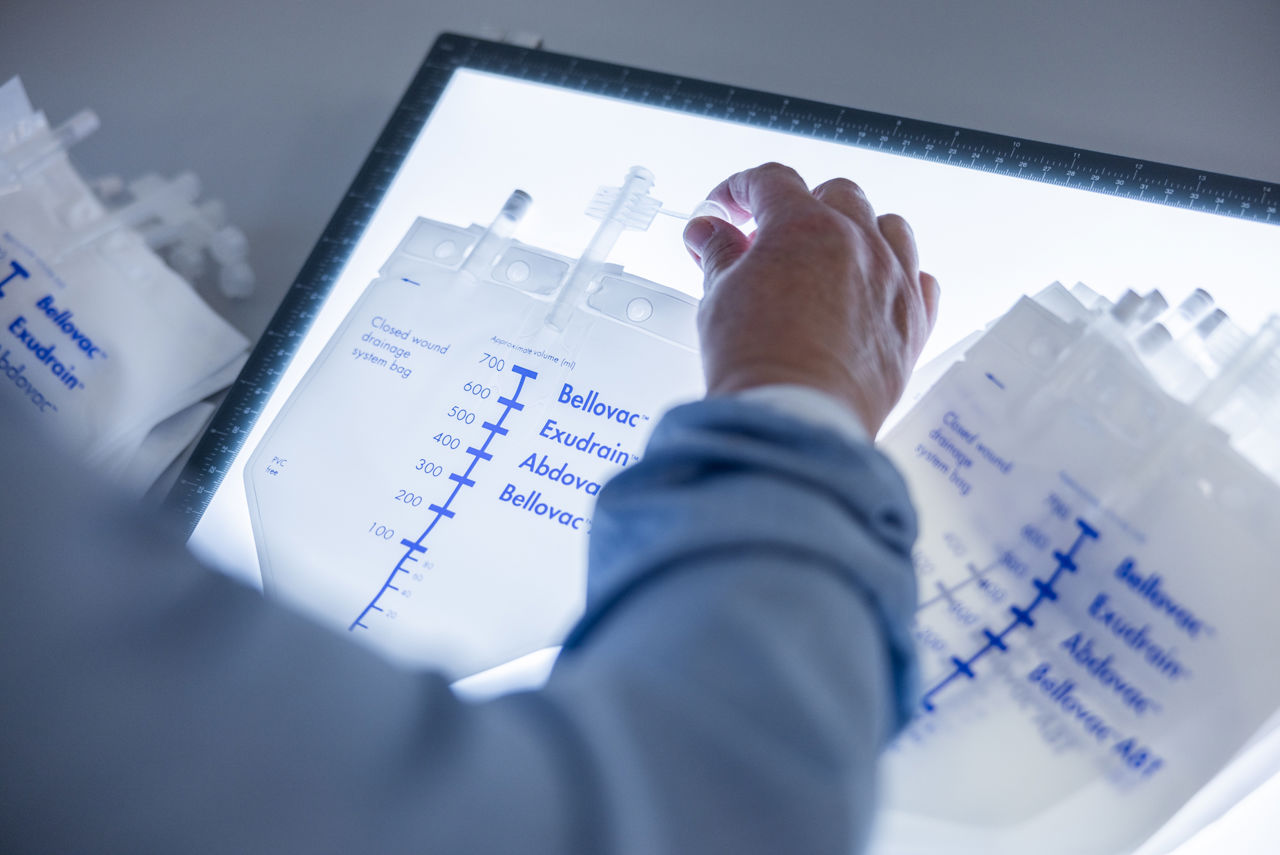 Händer som synar en produkt över ett ljusbord.