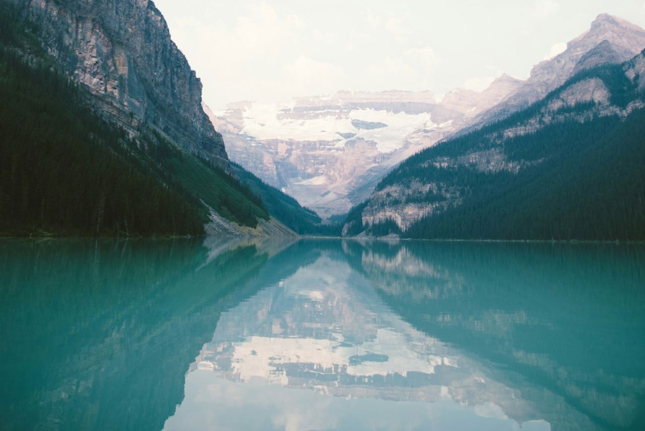 A still lake with mountaintops reflected on its surface.